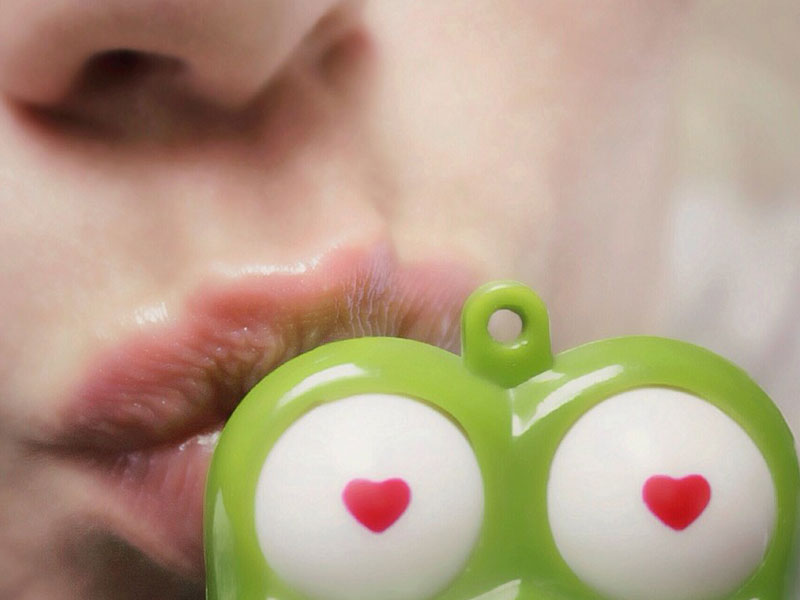 A girl kissing a plastic frog.