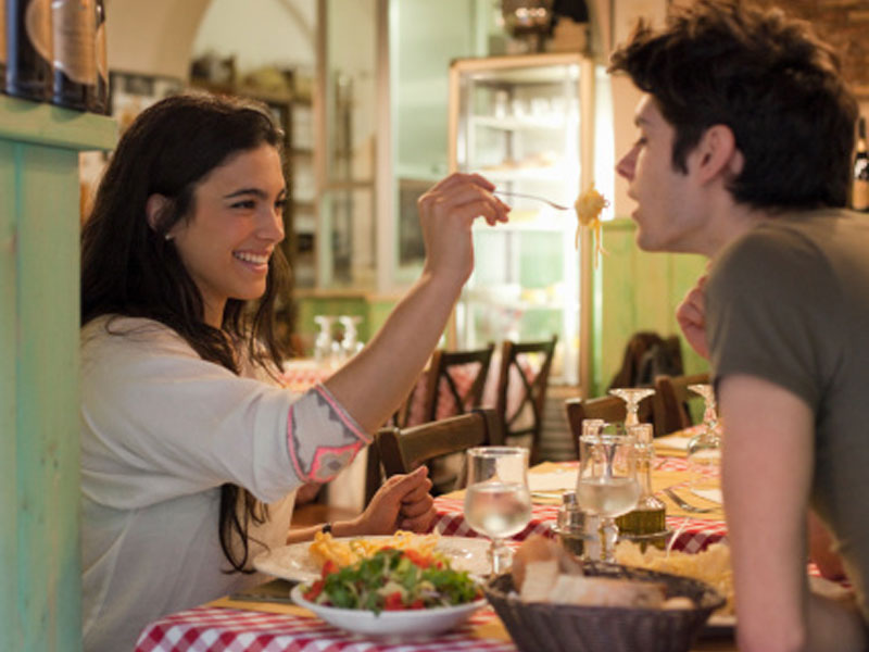 A couple laughing and eating dinner together on their first date.