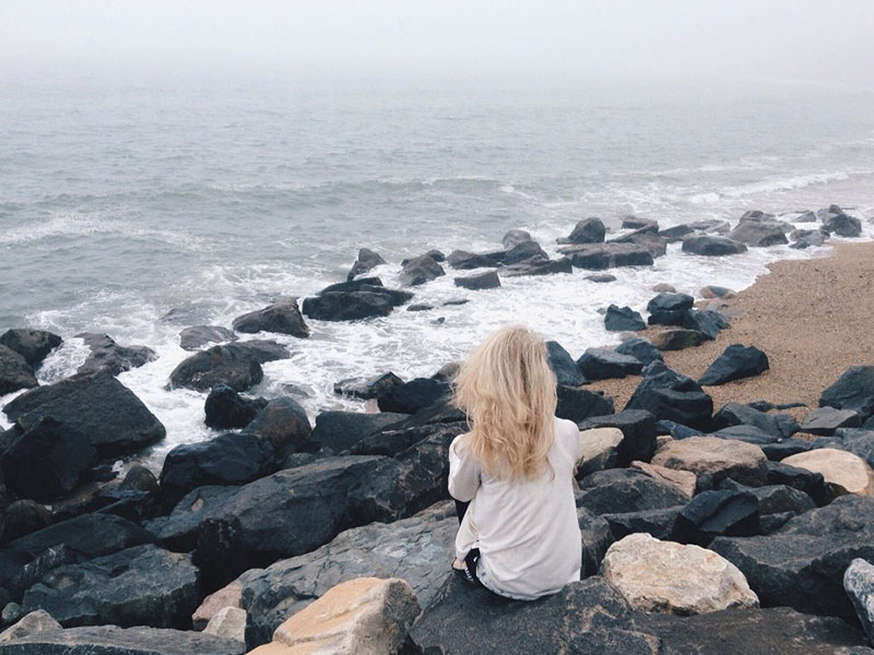 A woman having relationship problems and dealing with long distance at the beach thinking.