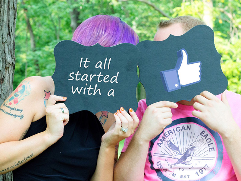 Two people at a wedding holding up signs saying it all started when they friended on Facebook.