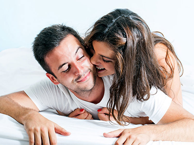 A healthy couple flirting in bed.