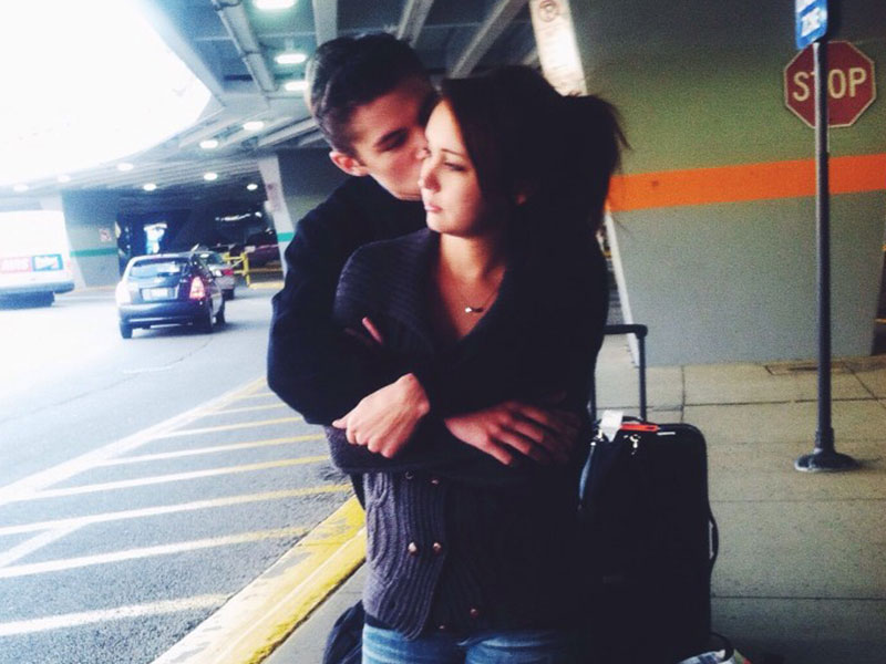 A couple in a long-distance relationship hugging each other at the airport after not seeing each other for a while.