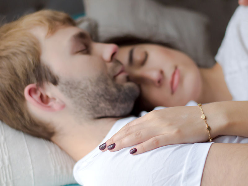 A couple relaxing and snuggling in bed after having make up sex.