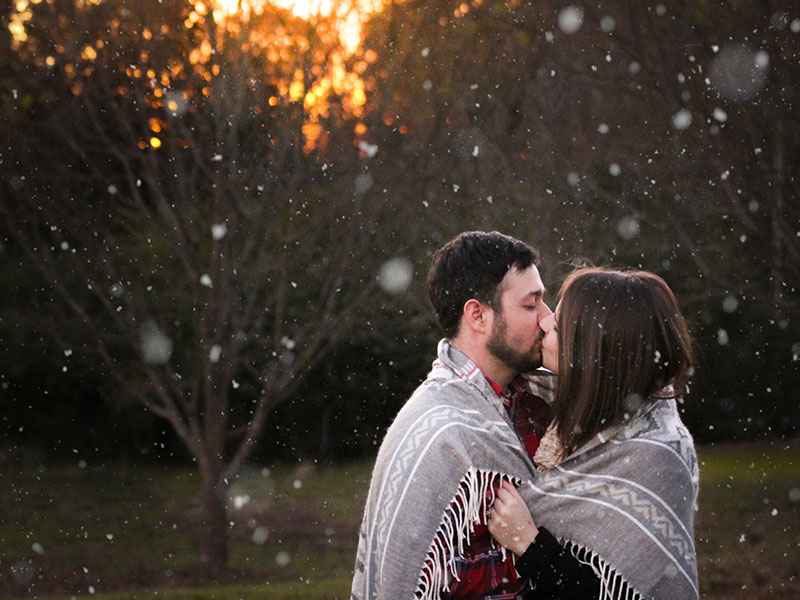 A couple in a healthy relationship who set good relationship goals kissing in the dimming light.