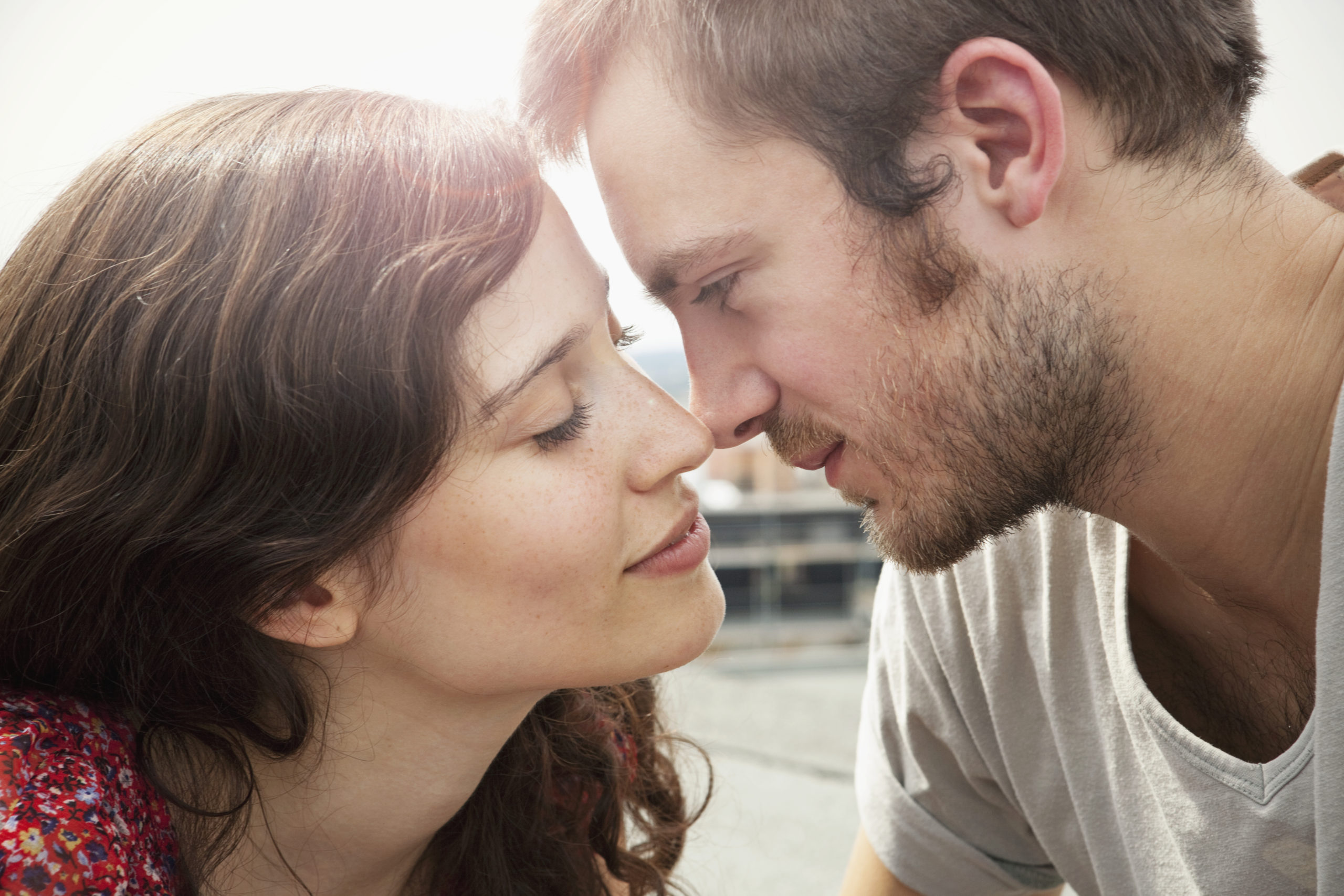 Couple in an exclusive relationship looking closely into each other's eyes while preparing to kiss.