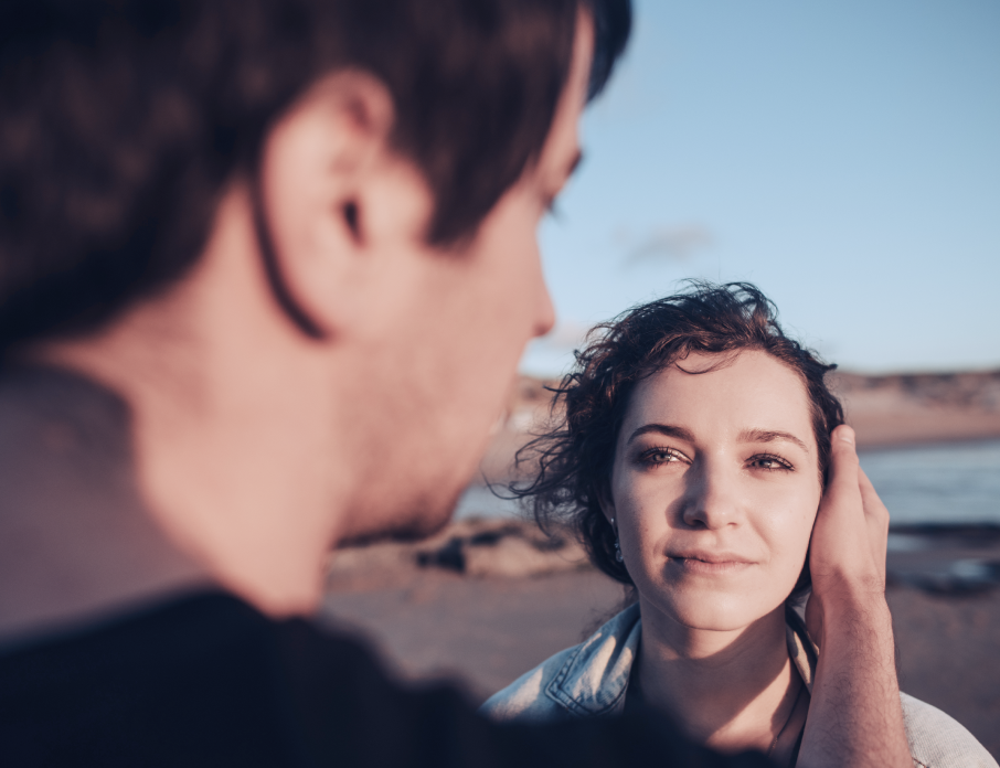 Happy couple standing outdoors while woman looks into the man's eyes and asks herself the question, "Is he the one?"