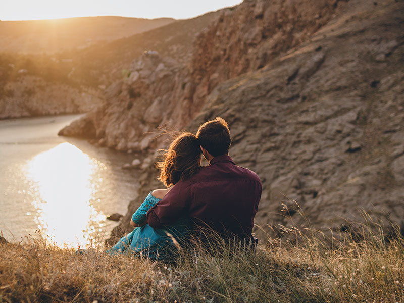 A woman who's dating after 40 watching a sunset with a man.
