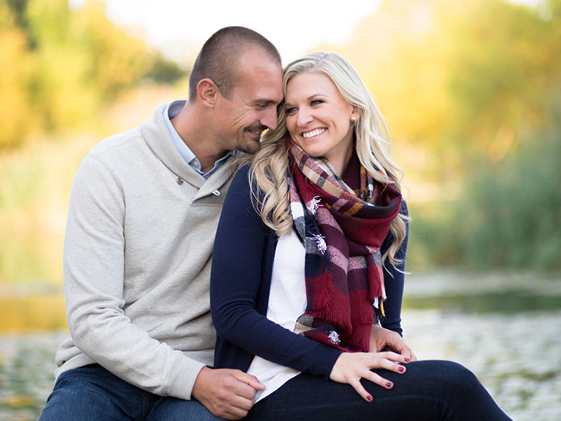 A man who's dating an older woman kissing her cheek by a lake.