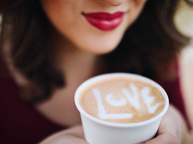A woman who's single in her 40s sipping from a coffee cup that says love in it.