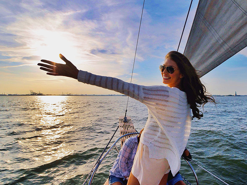 A woman who got help on how to move on, celebrating and looking happy on a boat during a sunny day.