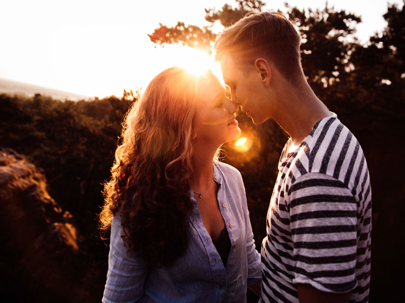 This woman figured out the six things guys do when they like you and is happy kissing her boyfriend in the sun.