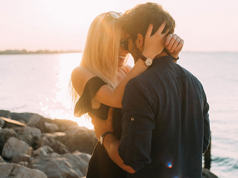 A woman hugging a man on a beach.
