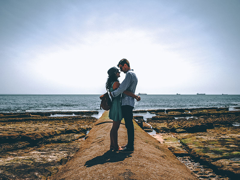 A couple being single in the summer and hugging on the beach.