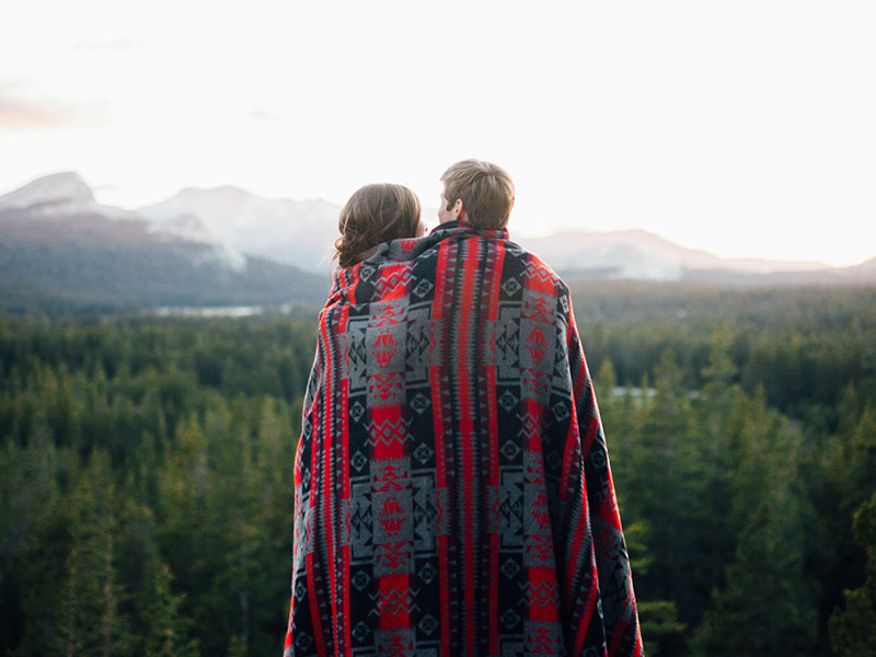 A couple who took these dating tips for frequent travelers and are now looking at a mountain and hugging.