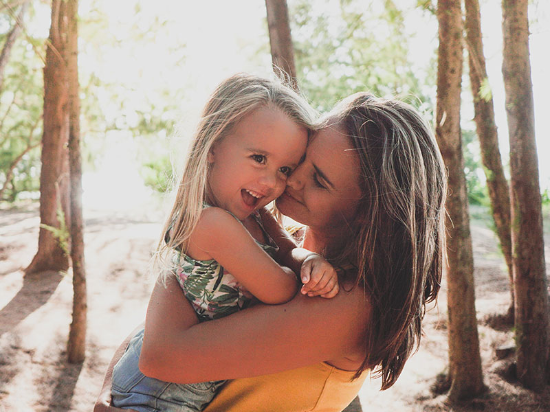 A mom who took these dating tips for single moms into account and is now happy and hugging her daughter in a forest.