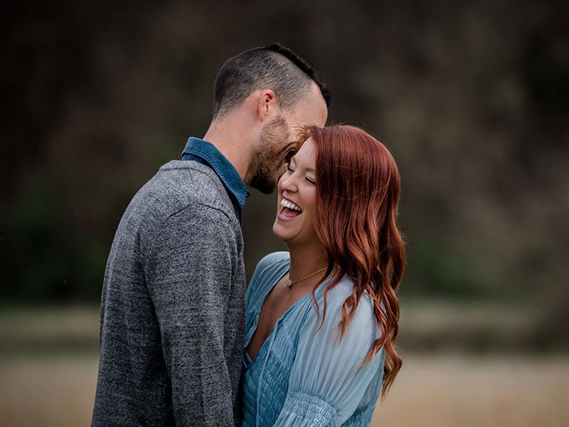 A woman with a man laughing over outdated dating tips for women she didn't use.