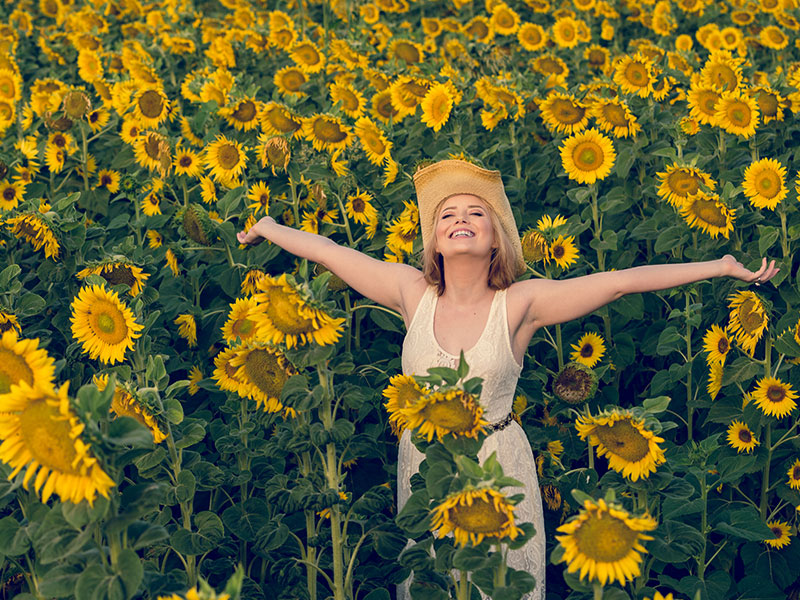 A women being single and happy in a field of sunflowers.