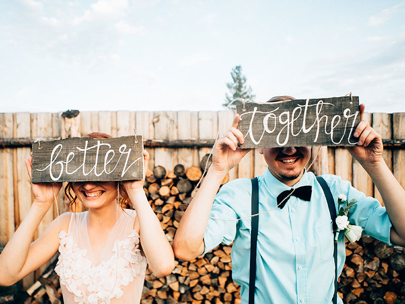 A couple holding up signs at their wedding that say better together.