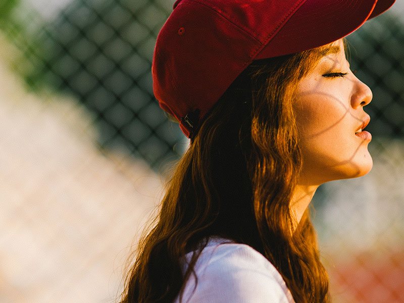 A women who's in the middle of getting over a bad breakup closing her eyes and breathing slowly as she faces the sunlight.