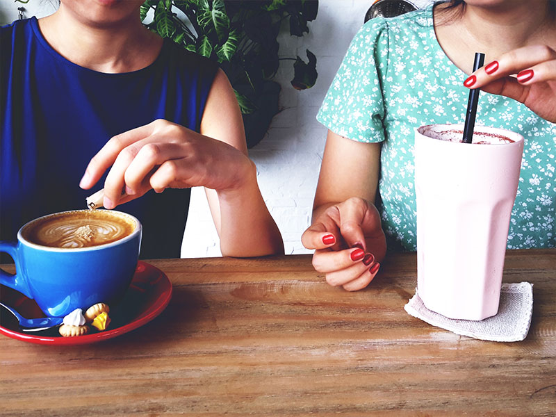 Two people who met while online dating in recovery drinking coffee and a milkshake on a date.