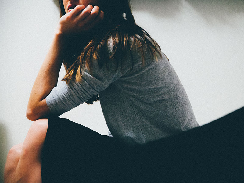 A woman who is lonely in marriage, thinking about how to talk to her husband while sitting in a room.