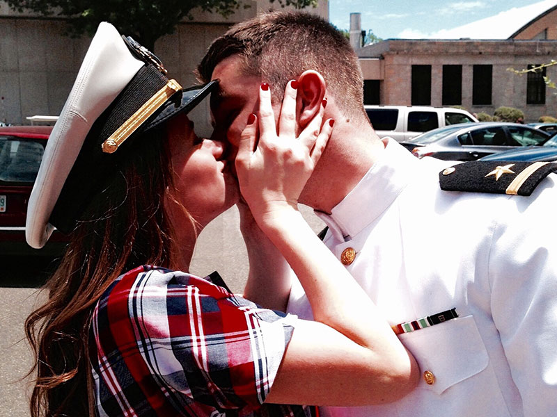 A woman kissing her boyfriend who's in the military because of their military love stories.
