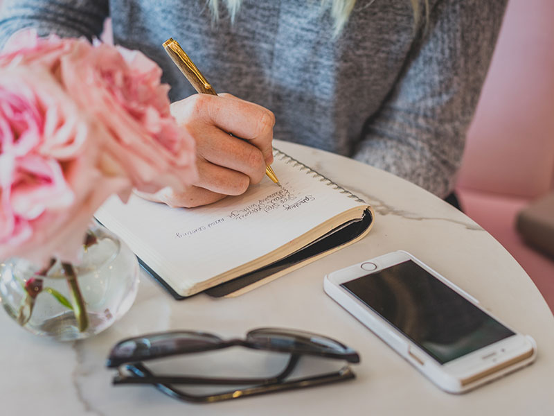 A professional matchmaker writing in her notebook while planning a date for someone.