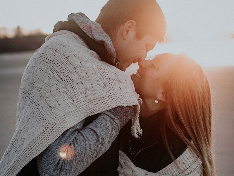 A woman who used to get dating anxiety, kissing her date on the beach and smiling.
