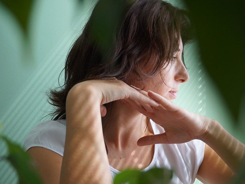 A woman who's wondering if her date is abusive, looking out a window and thinking.