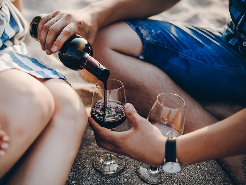 A couple coming up with things to talk about on a second date while pouring wine on the beach.