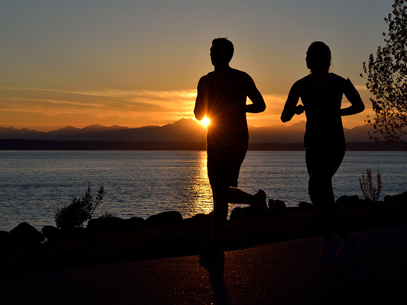 A couple who listened to these dating tips for runners, running at sunset together.