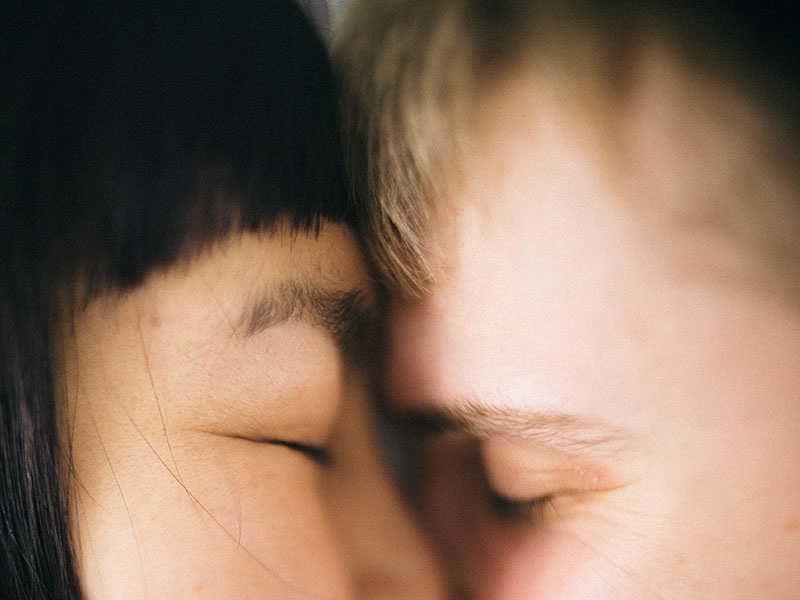 A couple in a tumultuous relationship closing their eyes as they hug.