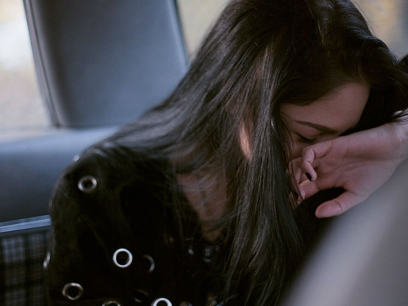 A girl who wondered do guys like shy girls, laughing and covering her face while a guy flirts with her.