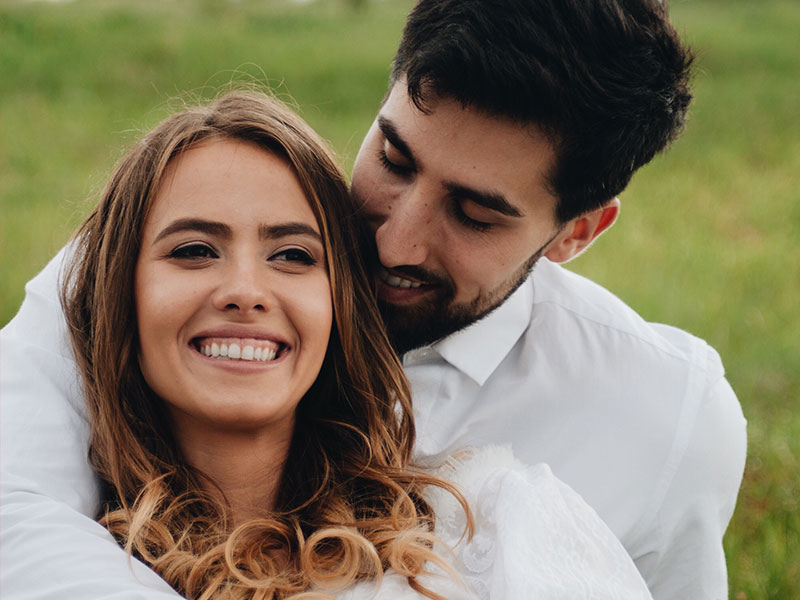 A girl who figured out what to look for in a guy, sitting with her boyfriend and smiling in the park.
