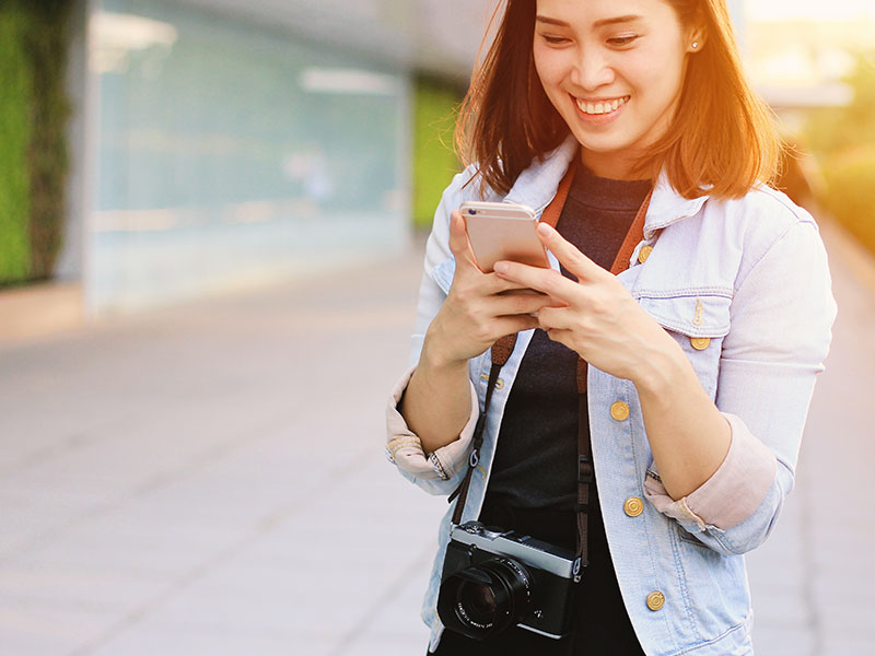 A girl who was wondering how does Hinge work, smiling as she texts on her phone to a guy she matched with.