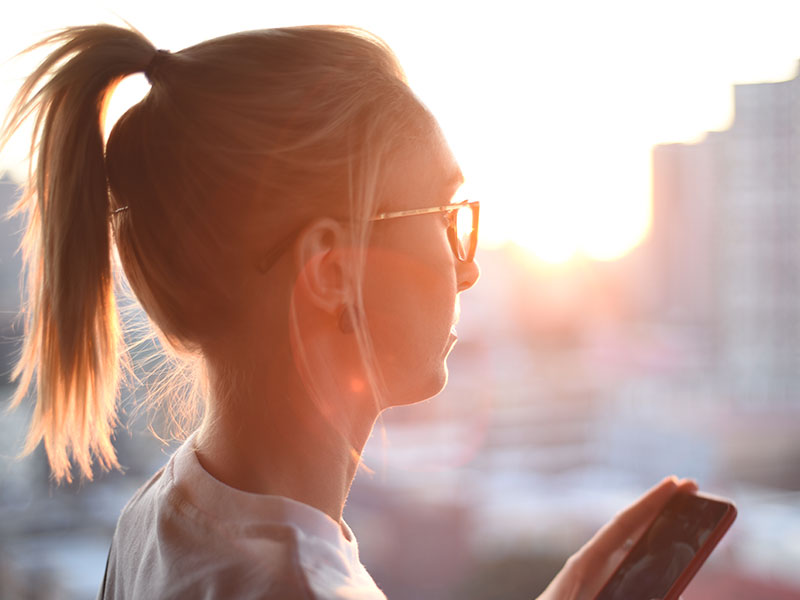 A woman who's following the no contact rule, holding her phone and thinking about calling her ex but resisting.