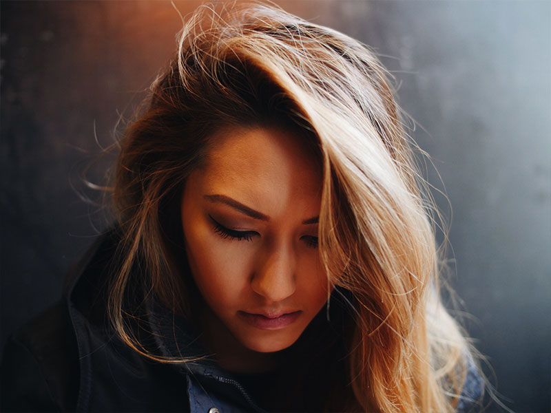 A woman who looked at the reasons to break up and knows she has a hard choice to make, looking down.