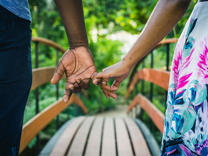A woman looking for signs a shy guys likes you holding hands with a shy guy as they hang out.