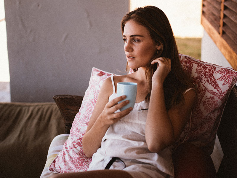 A woman who's learning how to let go of someone you love, sitting with her coffee and thinking.