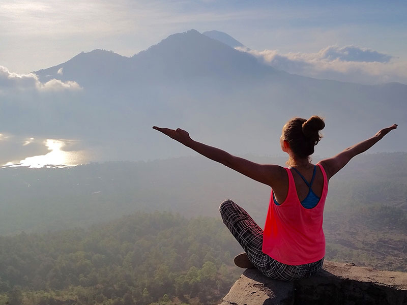 A women who's letting go of anger sitting on a mountaintop embracing the air.