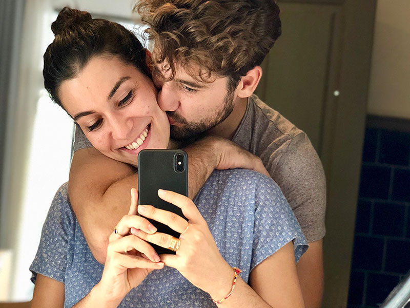 A man who was wondering are we dating, looking in the mirror with the woman he’s interesting in and hugging her.