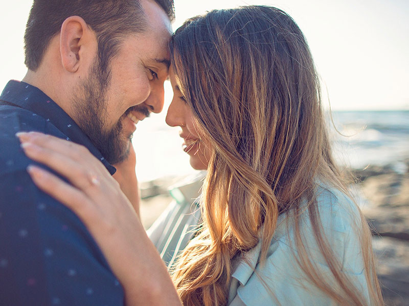 A couple in a relationship about to kiss on a beach.
