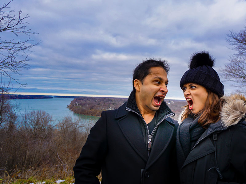 A couple having a mock petty argument and making funny fighting faces.