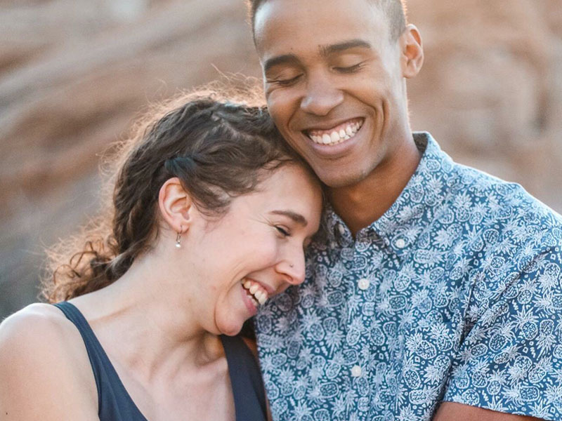A happy couple who learned how to give and get respect in a relationship laughing in the sunshine as they hug each other.