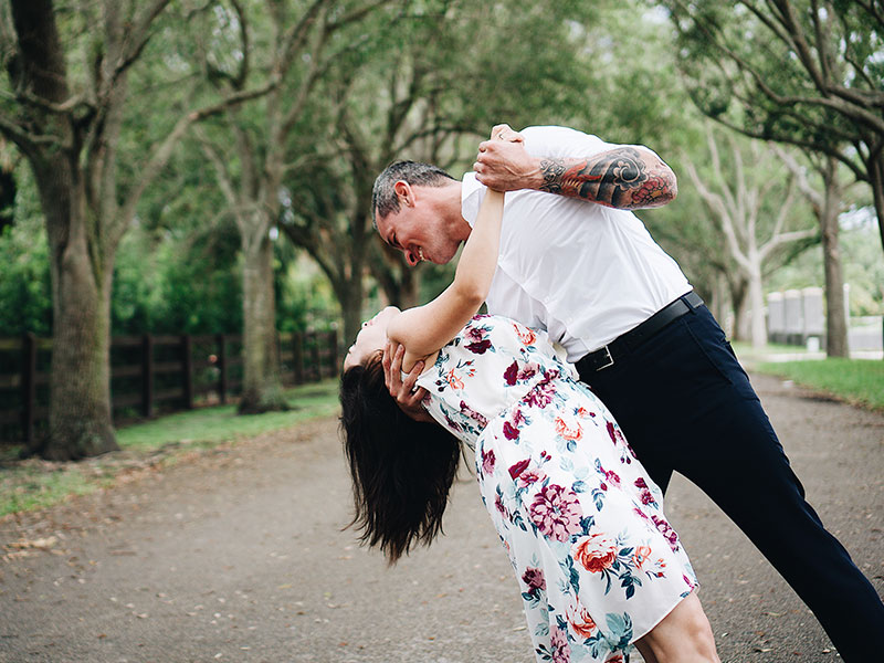 A couple in the senior dating scene, dancing in the park and laughing as the man dips the woman.