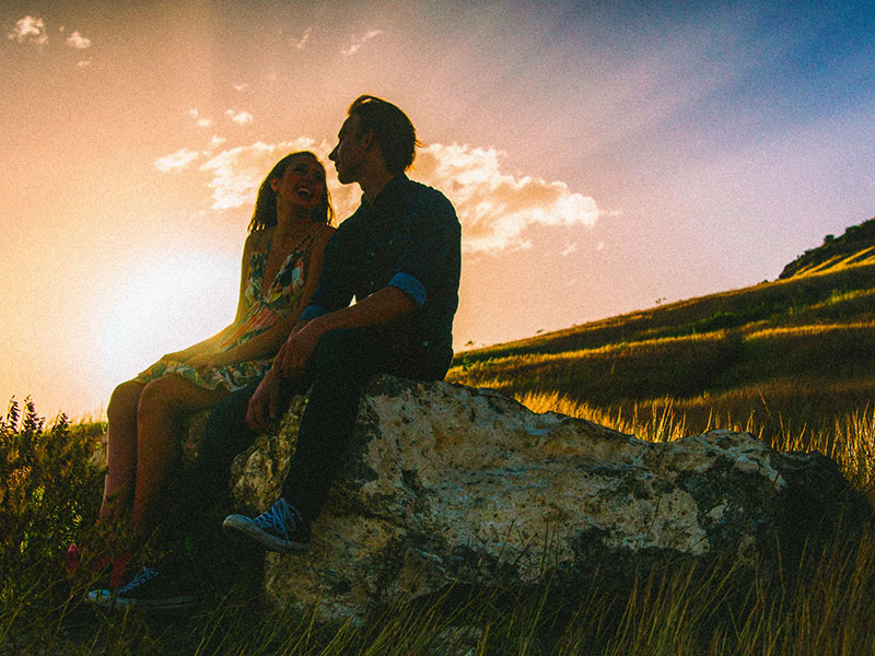 A couple who have consummate love, sitting next to each other at sunset.