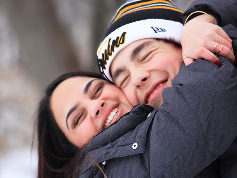 A woman and her boyfriend who learned these dating tips by living through them hugging and smiling like a couple of goof balls.