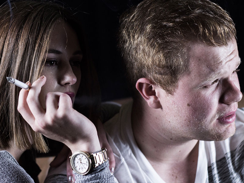 A woman smoking next to her date who thinks smoking is one of his main deal breakers.