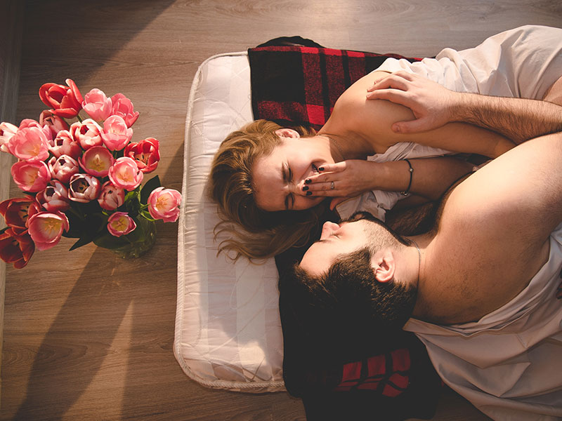 If you're wondering how to spice up your relationship, this couple laughing and flirting on a mattress on the floor surrounded by flowers may have an idea.