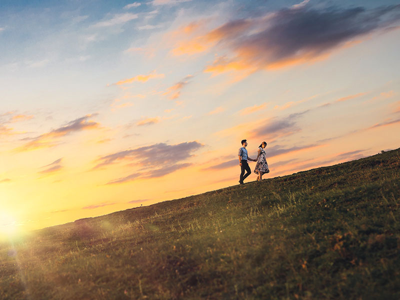 A couple who listened to this relationship advice climbing a mountain at sunset together.